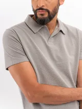 Remera tipo polo de manga corta con textura cloqué en color gris, de corte clásico y cuello camisero con abertura frontal.