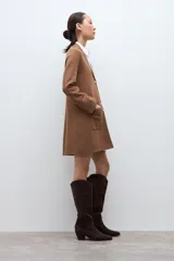 Sacón azul marino de corte largo, con cuello solapa, cierre frontal de dos botones dorados y bolsillos de parche.