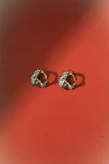 Aros de diseño orgánico con textura irregular y acabado metálico plateado, con cierre de perno.