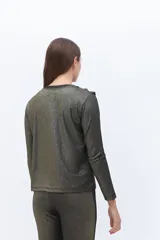 Remera de manga larga confeccionada en tejido de lurex negro con destellos dorados. Detalle de volados en el cuello tipo collar.