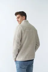 Campera de sherpa color verde militar, con cierre frontal completo, cuello alto y bolsillos laterales con cierre. Presenta un parche pequeño con logo en el pecho.