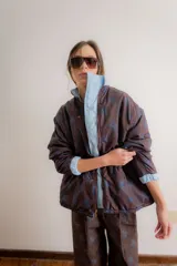 Campera reversible de estilo parka, color celeste, con diseño capitoneado con patrón de flores. Presenta ajuste elástico en la cintura, cuello alto y mangas largas. Incluye parche de marca en la parte superior de la espalda.