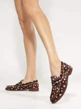 Mocasines Schutz modelo Tyche de cuero con pelo, diseño animal print marrón y blanco con efecto jaspeado, talón bajo y detalle de antifaz en el empeine con aplique metálico.