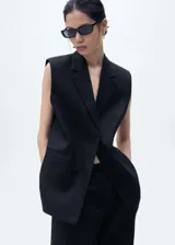 Chaleco tipo blazer sin mangas, de corte oversize y tejido de lino. Presenta cuello con solapas de muesca, bolsillos laterales de ribete y diseño abierto sin cierre.