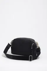 Bolso bandolera mediano de nylon negro con estructura blanda, detalles en piel, asa de hombro combinada de piel y cordón decorativo blanco y negro, cierre de cremallera y logo metálico de la marca.