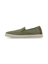 Alpargatas slip on RKF modelo Camaeli, color verde militar, confeccionadas con materiales reciclados. Presentan diseño de punta redonda, detalles elásticos en los laterales para un calce fácil, suela revestida en yute trenzado y un sutil bordado lateral de espina de pescado.