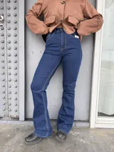 Jean de tiro alto con corte acampanado, confeccionado en denim azul oscuro con costuras en contraste.