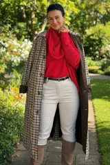 Trench reversible de corte largo, con un lado en color tostado liso y el otro lado con estampado de cuadros. Presenta cuello solapa, cierre frontal de botones, bolsillos laterales y puños con detalle de estampado a cuadros.