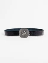 Cinto de cuero negro con hebilla hexagonal grande de metal plateado con diseño grabado y centro floral con tachas esféricas.