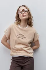 Remera blanca de silueta amplia y calce relajado, confeccionada en tela suave y liviana, con cuello redondo, mangas cortas con vuelta y hombros caídos. Cuenta con un delicado bordado frontal en color azul con la inscripción "LE SOLEIL TOUTE L'ANNÉE sur la Côte d'Azur".