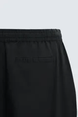 Pantalón de corte relajado color beige confeccionado en tejido de mezcla de algodón y lino. Posee cintura elástica ajustable con cordón, bolsillos frontales y bolsillos traseros de vivo.