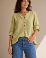 Blusa de lino color verde lima con cuello en V, cierre frontal con botones de madera y mangas largas con presilla para arremangar.