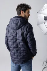 Campera de nylon termosellada con capucha, color azul marino, con cierre frontal y detalles en color naranja en el borde del cierre y costuras de la capucha.