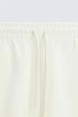 Bermuda de algodón color beige claro, corte relajado (relaxed fit), con cintura elástica ajustable mediante cordón y bolsillos laterales y trasero de plastrón.