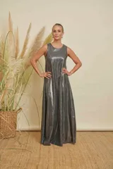 Vestido largo de corte amplio y línea simple, confeccionado en tejido de jersey con acabado metalizado plateado. Presenta cuello redondo y diseño sin mangas.