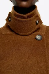 Chaquetón corto de corte recto confeccionado en lana doble faz, con doble botonadura frontal, cuello con solapa y manga larga. Presenta bolsillos en costura y barbuquejo en el cuello.