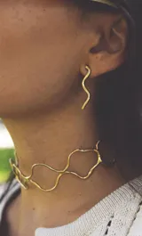 Aros colgantes dorados con forma de serpiente ondulada.