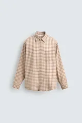 Camisa de corte relajado confeccionada en tejido fluido con algodón. Presenta un diseño de cuadros, cuello solapa, manga larga con puño abotonado, bolsillo plastrón en el pecho y cierre frontal con botones.