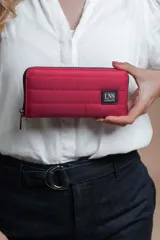 Billetera larga con cierre perimetral, confeccionada en nylon capitoneado color verde petróleo. Cuenta con correa de mano desmontable con logo estampado y parche frontal con marca LNS.