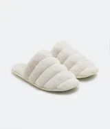 Pantufla cerrada de diseño acolchado con gajos, confeccionada en tejido de textura felpuda suave, con suela de goma termoplástica.