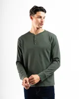 Remera tipo henley de manga larga confeccionada en tejido de algodón con textura mini piqué. Presenta un cierre frontal con tres botones y puños ajustados en las mangas.