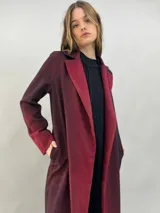Tapado de paño de lana con diseño de solapas amplias, corte recto y bolsillos laterales ocultos. Presenta un degradado de color que va desde un tono bordó intenso en las solapas y puños hacia un tono más oscuro en el cuerpo.