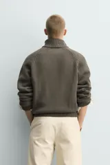 Chaqueta relaxed fit de punto tejido en hilatura con mezcla de algodón, color beige, con cuello subido y manga larga. Cuenta con acabados en rib, efecto lavado y cierre frontal con cremallera.