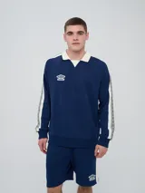 Buzo azul marino Umbro con cuello polo blanco, bandas blancas en las mangas con estampado gráfico y logo de la marca bordado en el pecho.