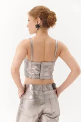 Top tipo corset plateado de cuero ovino, con tirantes finos regulables y cierre trasero con cremallera.