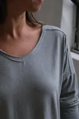 Remera de algodón gris con cuello en V, mangas largas y corte holgado con ruedo asimétrico.