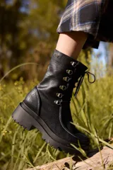 Borcego de caña corta confeccionado en cuero, con diseño de cordones y ganchos metálicos, cierre lateral y suela track de plataforma.