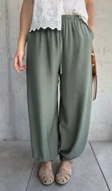 Pantalón tipo babucha de color verde militar, con cintura elástica fruncida y cordón ajustable. Cuenta con diseño amplio y puños elásticos en los tobillos.