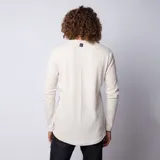 Buzo de manga larga con cuello redondo, confeccionado en tela tipo waffle de color beige. Presenta un corte long-fit con ruedo redondeado, ofreciendo un estilo relajado y moderno.