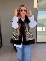 Chaleco reversible con un lado de piel sintética negra y otro lado de tela bordada con diseño paisley y floral en tonos oscuros. Presenta un corte amplio y sin mangas.