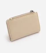 Billetera pequeña tipo sobre Satinato, color beige, confeccionada en poliuretano con textura símil cuero. Cuenta con cierre de cremallera superior, compartimento exterior para tarjetas y aplicación metálica triangular con el logo de la marca en el frente.