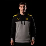 Canguro con capucha Puma del Club Atlético Peñarol. Diseño de bloques de color con cuerpo gris, mangas y parte superior negras, y detalles en amarillo en los hombros. Incluye logo de Puma y escudo del club en el pecho, además de un bolsillo frontal tipo canguro.