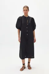 Vestido midi negro confeccionado en lino, con cuello mao, mangas abullonadas hasta el codo y cierre frontal con botones de nácar.