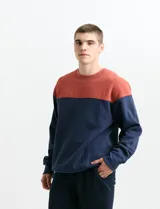 Sweater de tejido circular con diseño color block, combinando una franja superior en color verde y el resto de la prenda en gris oscuro. Presenta cuello redondo y puños en tejido canalé.