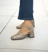 Zapato de cuero vacuno color gris topo, con talón descubierto y pulsera con hebilla. Tiene taco de madera forrado en cuero y suela de goma. La horma es de punta cuadrada, ancha y cómoda.