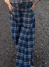 Pantalon de corte recto y tiro alto con estampado de cuadros en tonos azul, negro y beige. Presenta un diseño clásico con cierre frontal y bolsillos laterales.