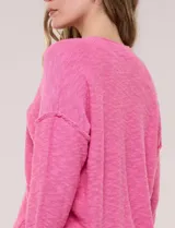 Cardigan blanco de punto liviano y texturado, de corte holgado y diseño casual. Cuenta con escote en V pronunciado, abotonadura frontal, mangas largas con hombros caídos y bolsillos delanteros tipo parche.