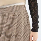 Falda corta estilo globo con estampado de cuadros pequeños en tonos beige y marrón. Presenta una cintura elástica cómoda y un corte voluminoso característico del diseño tipo globo.