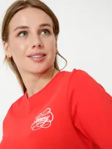 Vestido rojo de algodón con cuello redondo y mangas cortas. Presenta un logo de Tommy Hilfiger bordado en blanco en el pecho y la bandera de la marca bordada en la manga.