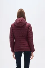 Campera acolchada tipo puffer, color beige claro, con capucha y cierre frontal. Presenta costuras horizontales y un calce entallado.