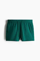 Short de baño de sirsaca color verde esmeralda, con cintura elástica y cordón ajustable. Presenta aberturas laterales cortas, bolsillos laterales y un bolsillo trasero con cierre autoadherente. Incluye suspensor interior de malla.