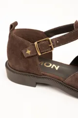 Sandalias cerradas de cuero marrón, con diseño tipo Mary Jane con tira en T, detalles perforados en la puntera y suela plana con pequeño tacón.