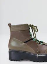 Botas de cuero estilo trekking, en combinación de colores verde, marrón y gris, con plataforma de goma negra, cordones bicolor inspirados en cuerdas de escalada y pasadores en tono rojizo.