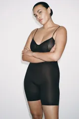 Body tipo shorts de color negro con diseño de efecto visual ondulado. Presenta escote en pico, tirantes finos ajustables y confección en tejido de poliamida con efecto reductor.