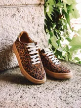 Zapatillas de cuero con estampado animal print tipo leopardo, cordones blancos y suela plana de goma.