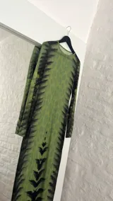 Vestido midi ajustado de microtul verde con estampado abstracto en tonos oscuros. De mangas largas y cuello redondo, es una prenda transparente y elástica.